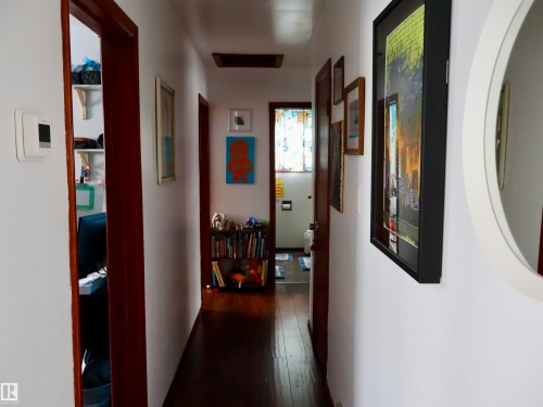 Interior hallway featuring hardwood floors, white walls, and dark wood door frames - 4315 56 Avenue, Barrhead, AB - Indoor Photo Showing Other Room