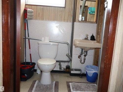 The bathroom features a toilet, a wall-mounted sink, and a mirror - 4315 56 Avenue, Barrhead, AB - Indoor Photo Showing Bathroom