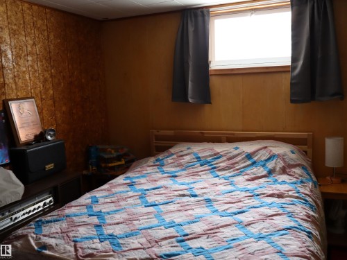 Bedroom featuring a window with dark curtains, wood paneled walls, and a wood bed frame - 4315 56 Avenue, Barrhead, AB - Indoor Photo Showing Bedroom