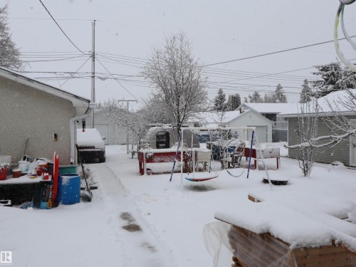 The property features a spacious backyard with a snow-covered lawn and mature trees - 4315 56 Avenue, Barrhead, AB - Outdoor