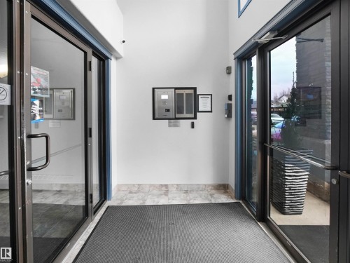 The entrance features glass doors with dark frames, a light-colored tiled floor, and a grey floor mat - 106 2305 35A Avenue Nw, Edmonton, AB -  Photo Showing Other Room
