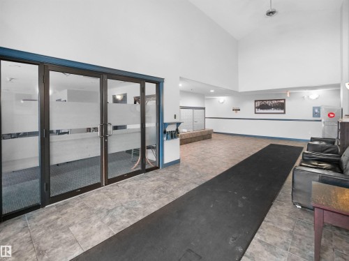 The property features a spacious entry area with tiled flooring, a high vaulted ceiling, and glass-paned doors - 106 2305 35A Avenue Nw, Edmonton, AB -  Photo Showing Other Room