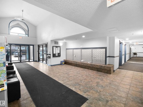 The property features a spacious common area with tile flooring and a high ceiling - 106 2305 35A Avenue Nw, Edmonton, AB - Indoor Photo Showing Other Room