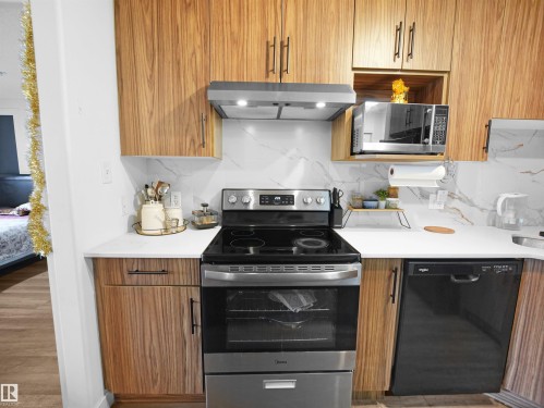 The kitchen features wood-toned cabinetry, white countertops, and a white and grey marble-effect backsplash - 106 2305 35A Avenue Nw, Edmonton, AB - Indoor Photo Showing Kitchen