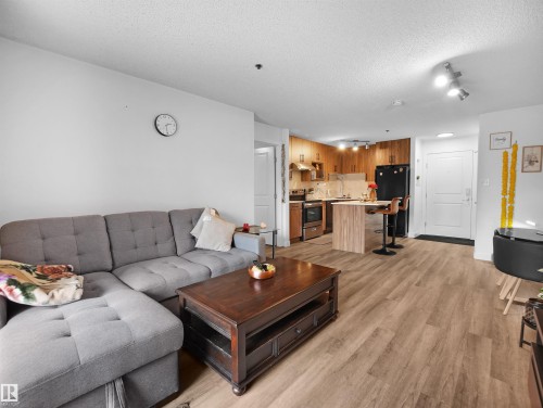 The property features an open-concept living area and kitchen with light-colored flooring throughout - 106 2305 35A Avenue Nw, Edmonton, AB - Indoor Photo Showing Living Room