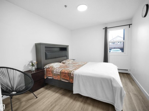 This bright room features light-toned flooring, white walls, and a window providing natural light - 106 2305 35A Avenue Nw, Edmonton, AB - Indoor Photo Showing Bedroom