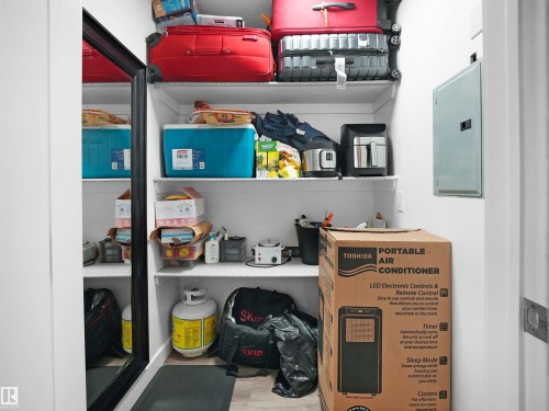 The property offers a storage area with white shelving and a full-length mirror - 106 2305 35A Avenue Nw, Edmonton, AB - Indoor Photo Showing Other Room