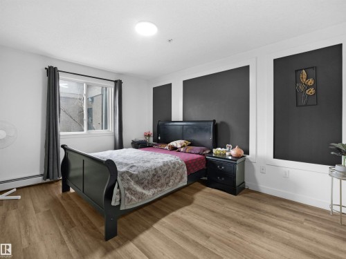 Bedroom featuring light-toned flooring, a window with dark curtains, and an overhead light fixture - 106 2305 35A Avenue Nw, Edmonton, AB - Indoor Photo Showing Bedroom