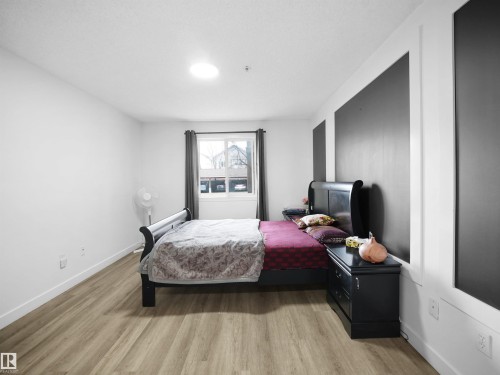 Bedroom featuring light-toned flooring, white walls, and a window with dark curtains - 106 2305 35A Avenue Nw, Edmonton, AB - Indoor Photo Showing Bedroom
