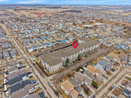 Aerial view of the property and its surrounding neighborhood, featuring residential streets, houses, and open fields in the background - 106 2305 35A Avenue Nw, Edmonton, AB - Outdoor With View
