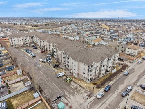 This property features a multi-story building with balconies, a large parking area, and a surrounding neighborhood - 106 2305 35A Avenue Nw, Edmonton, AB - Outdoor With View