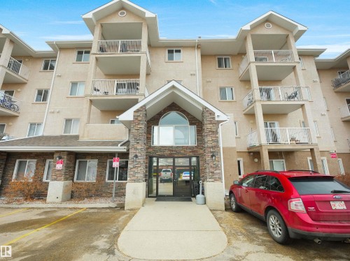 The property features a multi-story exterior with balconies and a stone facade entrance - 106 2305 35A Avenue Nw, Edmonton, AB - Outdoor With Facade