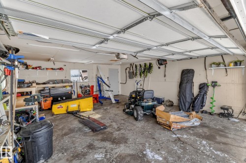 This property includes a spacious garage with a concrete floor, equipped with shelving for storage and a white overhead garage door - 160068 Twp 531, Rural Lamont County, AB - Indoor Photo Showing Garage