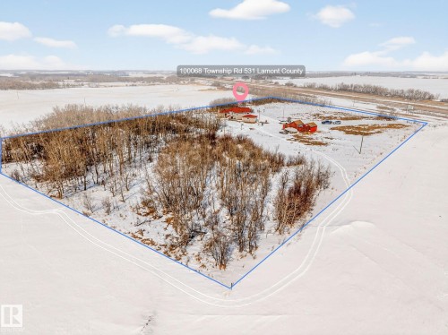 Aerial view of the property showing a main residence with a red roof, along with additional red-roofed outbuildings - 160068 Twp 531, Rural Lamont County, AB - Outdoor With View