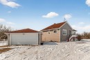 The property features a residence with gray and beige siding and a red roof, along with a separate garage structure with a white garage door and matching red roof - 160068 Twp 531, Rural Lamont County, AB  - Outdoor With Exterior 