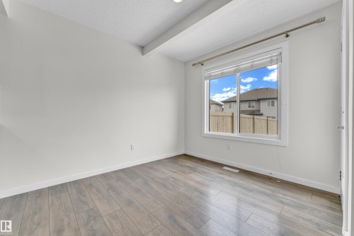 This room features light wood-look flooring, white walls, and a window with a view of a residential area - 4416 6 Street, Edmonton, AB - Indoor Photo Showing Other Room