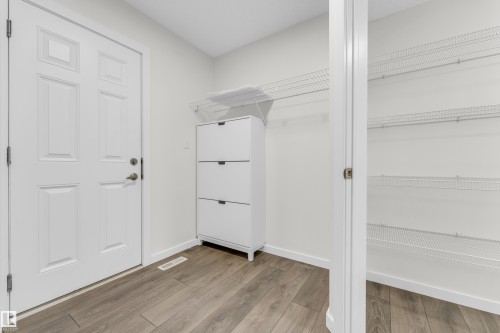 Entryway featuring wood-look flooring, a white paneled door, and a storage area with wire shelving - 4416 6 Street, Edmonton, AB - Indoor