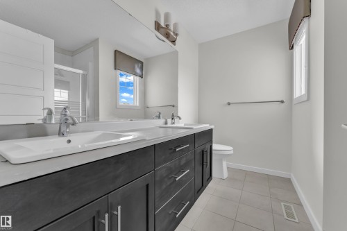 Bathroom featuring a double vanity with dark wood cabinetry, white countertops, and chrome fixtures - 4416 6 Street, Edmonton, AB - Indoor Photo Showing Bathroom