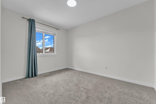 The property features a room with light grey carpet, white walls, and a window with a blue curtain - 4416 6 Street, Edmonton, AB - Indoor Photo Showing Other Room