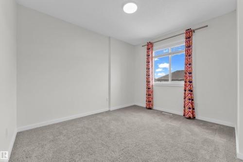 This room features light grey carpeting, white walls, and a window with colorful curtains - 4416 6 Street, Edmonton, AB - Indoor Photo Showing Other Room
