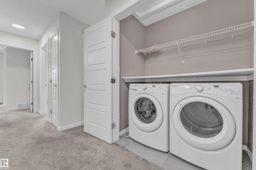 Laundry area featuring a front-loading washer and dryer, with shelving and a hanging rod for convenience - 4416 6 Street, Edmonton, AB - Indoor Photo Showing Laundry Room