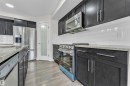 The kitchen features dark cabinetry with silver hardware, granite countertops, and a white subway tile backsplash - 4416 6 Street, Edmonton, AB  - Indoor Photo Showing Kitchen With Stainless Steel Kitchen With Upgraded Kitchen 