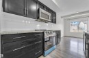 The kitchen features dark cabinetry, light countertops, a stainless steel microwave and range, and subway tile backsplash - 4416 6 Street, Edmonton, AB  - Indoor Photo Showing Kitchen With Upgraded Kitchen 