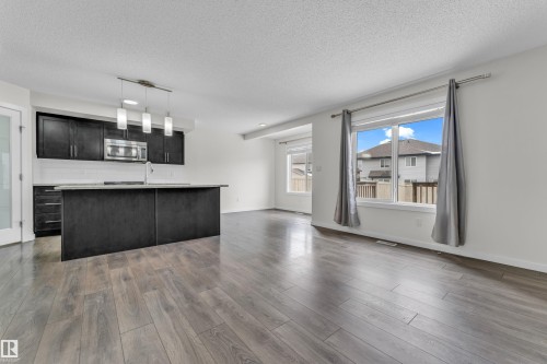 The open concept living area features sleek wood-style flooring and large windows with privacy curtains - 4416 6 Street, Edmonton, AB - Indoor