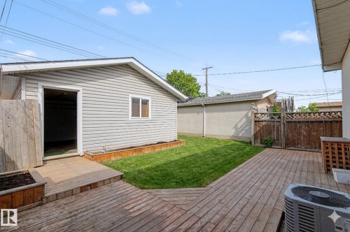The property features a backyard with a wrap-around wooden deck, lawn with custom built planters and detached double garage - 5920 132 Avenue, Edmonton, AB - Outdoor With Deck Patio Veranda With Exterior