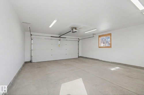 The property features an detached double garage with a concrete floor, a garage door, and a window with a wood frame - 5920 132 Avenue, Edmonton, AB - Indoor Photo Showing Garage