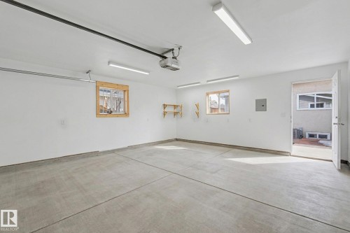Spacious garage featuring a concrete floor, bright overhead lighting, and two windows with wooden frames - 5920 132 Avenue, Edmonton, AB - Indoor