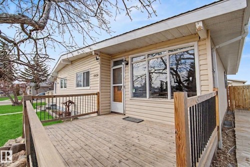 The property features a front deck with wooden railings, a light-colored exterior siding, and large windows - 5920 132 Avenue, Edmonton, AB - Outdoor With Deck Patio Veranda