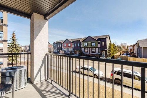 The property features a private balcony with a dark metal railing, offering views of the surrounding neighborhood and street - 209 14612 125 Street, Edmonton, AB - Outdoor With Balcony