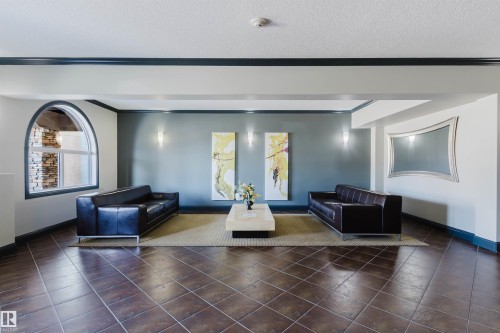 Spacious room featuring large tiled flooring, an arched window, and sconce lighting - 209 14612 125 Street, Edmonton, AB - Indoor