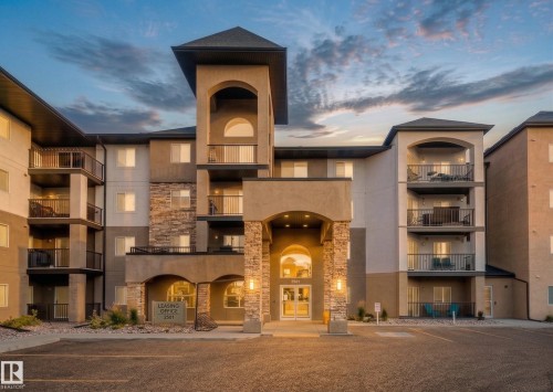 The property features an inviting entrance with stone accents, arched details, and multiple balconies - 209 14612 125 Street, Edmonton, AB - Outdoor With Balcony