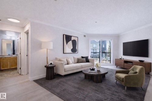 Spacious living area featuring light-colored flooring, a large area rug, and a sliding glass door leading to an outdoor space. This space has been virutually staged to show perspective. - 209 14612 125 Street, Edmonton, AB - Indoor Photo Showing Living Room