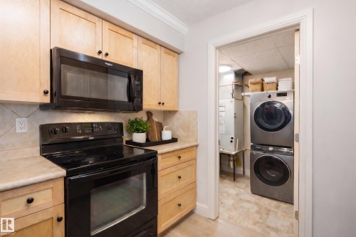 Kitchen featuring light wood cabinetry, a black oven, and an overhead microwave - 209 14612 125 Street, Edmonton, AB - Indoor Photo Showing Laundry Room