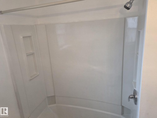 The bathroom features a white shower and bathtub combination with an integrated shelving niche and a chrome shower head and faucet - 3626 111 Avenue, Edmonton, AB - Indoor Photo Showing Bathroom
