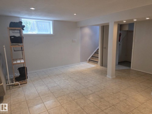 The property features a spacious room with light-colored tile flooring and recessed lighting - 3626 111 Avenue, Edmonton, AB - Indoor