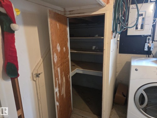This storage area features built-in shelving, a sturdy wooden door, and a concrete floor - 3626 111 Avenue, Edmonton, AB - Indoor Photo Showing Laundry Room