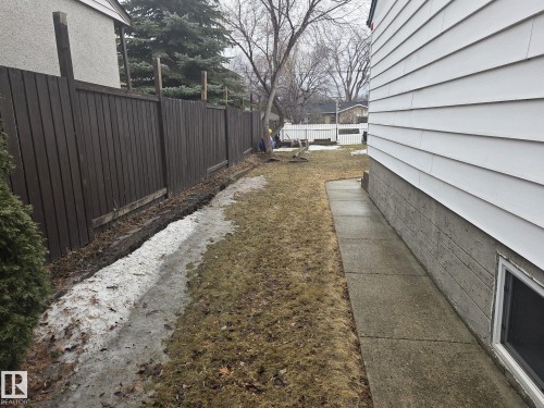 The property features a concrete walkway along the side of the residence and a dark wood fence - 3626 111 Avenue, Edmonton, AB - Outdoor
