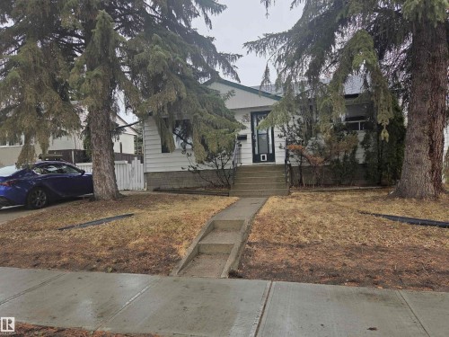 The property features a concrete walkway leading to the front entrance, a front yard with mature trees, and a white picket fence visible on the property line - 3626 111 Avenue, Edmonton, AB - Outdoor