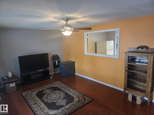 Living area with warm-toned walls, a ceiling fan with integrated lighting, and wood-look flooring - 3626 111 Avenue, Edmonton, AB - Indoor Photo Showing Other Room