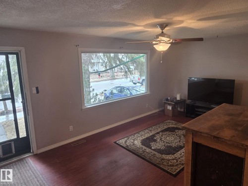 Living area featuring wood flooring, a ceiling fan with integrated lighting, and a large window - 3626 111 Avenue, Edmonton, AB - Indoor