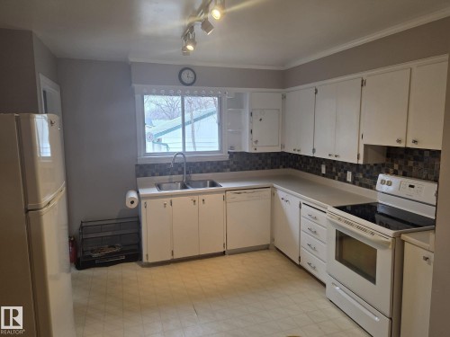 The kitchen features white cabinetry, a double basin sink, and a tiled backsplash - 3626 111 Avenue, Edmonton, AB - Indoor Photo Showing Kitchen With Double Sink