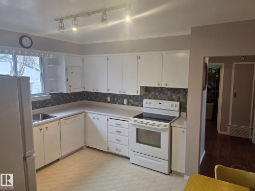 The kitchen features white cabinetry, a tiled backsplash, and track lighting - 3626 111 Avenue, Edmonton, AB - Indoor Photo Showing Kitchen
