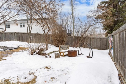 The property features a fenced yard with a fire pit area, mature trees, and a wooden fence - 10 Harmony Place, St. Albert, AB - Outdoor