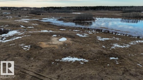Expansive acreage featuring natural terrain with varied vegetation, scattered snow patches, and a prominent body of water reflecting the sky - 57027 Sec Hwy 881, Rural St. Paul County, AB 