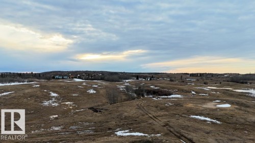 Expansive terrain featuring open fields with patches of snow, distant evergreen trees, and a visible horizon - 57027 Sec Hwy 881, Rural St. Paul County, AB 