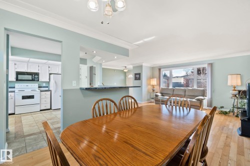 This property features an open living and dining area with hardwood flooring, light blue walls, and a large window - 2016 138 Avenue, Edmonton, AB - Indoor Photo Showing Dining Room